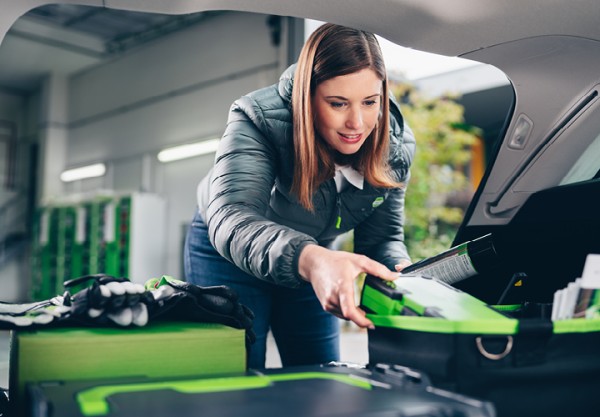 Außendienstmitarbeiterin holt Produkt aus Auto