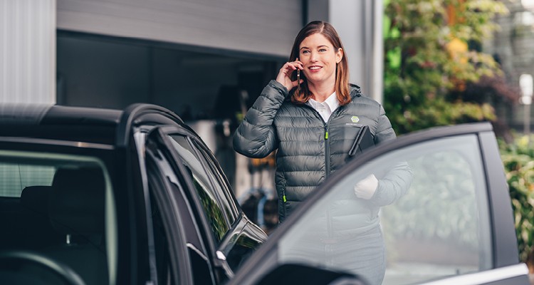 Außendienstmitarbeiterin telefoniert am Auto