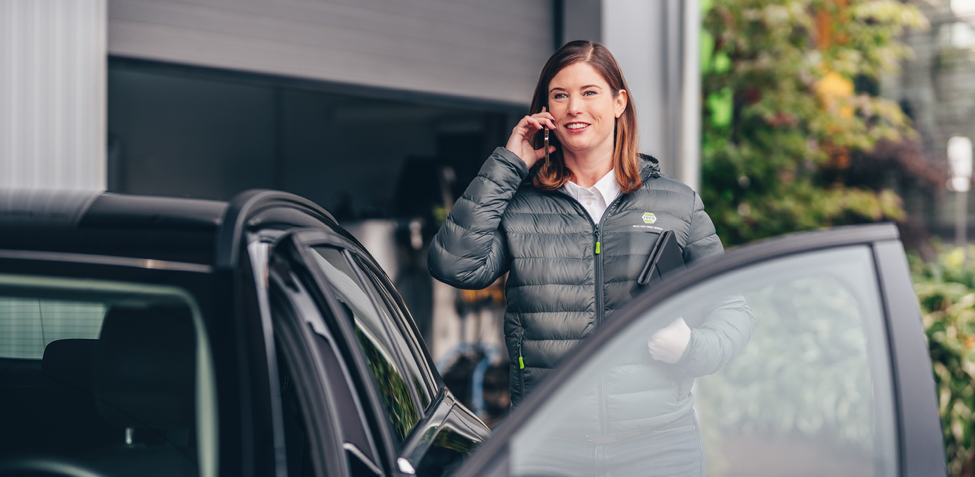 Außendienstmitarbeiterin telefoniert am Auto